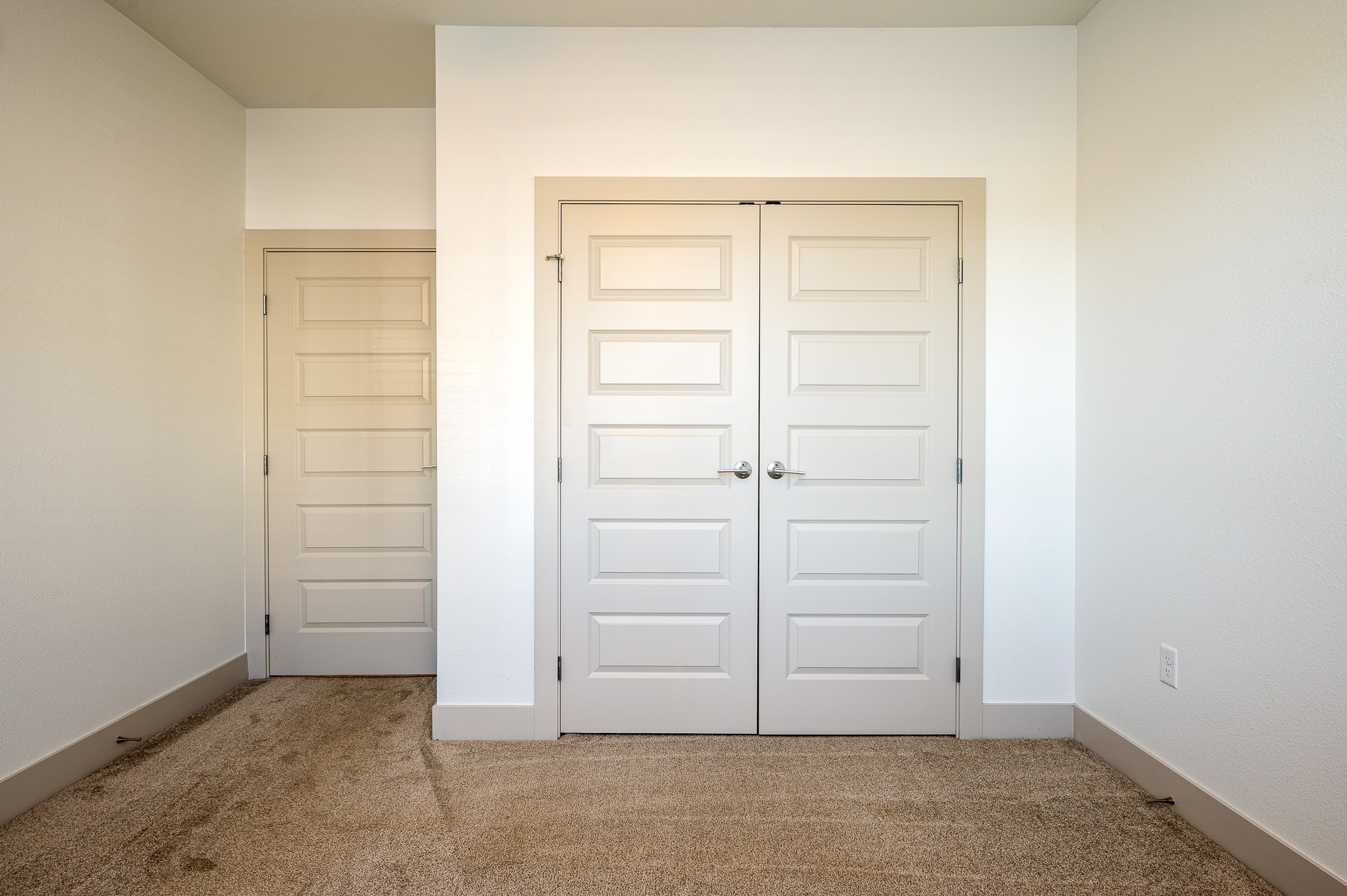 A room with large closet doors and a carpeted floor.